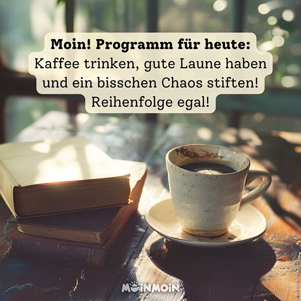 Kaffeetasse auf dem Tisch mit zwei dicken Büchern und Gruß: „Moin! Programm für heute: Kaffee trinken, gute Laune haben und ein bisschen Chaos stiften! Reihenfolge egal!"