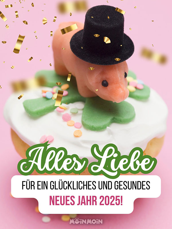 Schwein aus Marzipan mit einem Hut auf einem Kleeblatt mit Grüßen zu Neujahr darunter: „Alles Liebe für ein glückliches und gesundes neues Jahr 2025!"